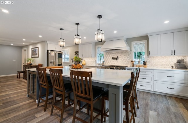 kitchen featuring dark wood-style floors, premium range hood, white cabinets, and stainless steel fridge with ice dispenser