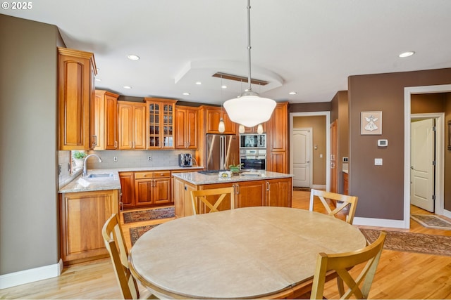 kitchen with light wood-type flooring, a sink, tasteful backsplash, a center island, and appliances with stainless steel finishes