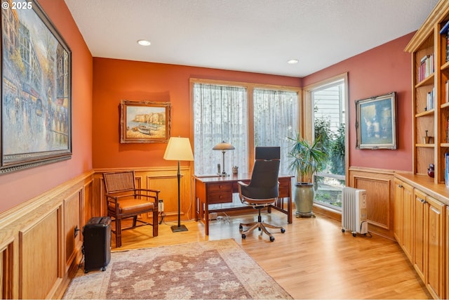 home office featuring a wainscoted wall, radiator heating unit, recessed lighting, a textured ceiling, and light wood-type flooring