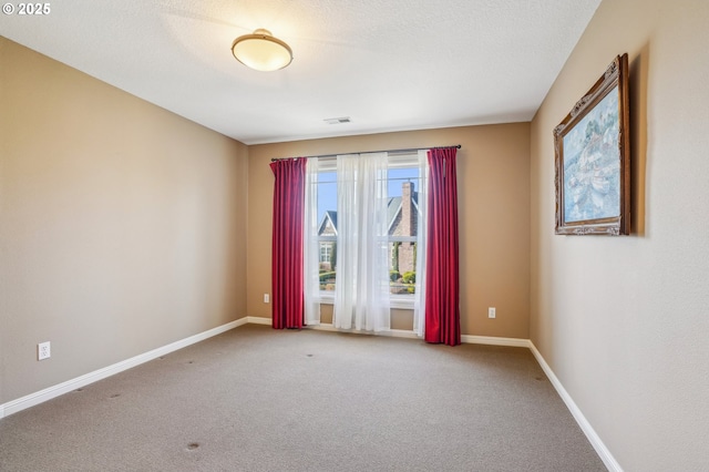 carpeted spare room with visible vents, baseboards, and a textured ceiling