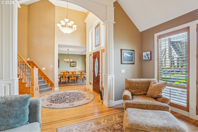 foyer entrance with arched walkways, high vaulted ceiling, an inviting chandelier, and hardwood / wood-style flooring