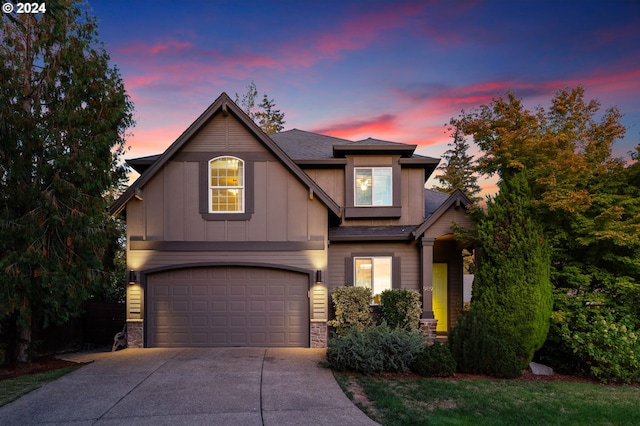 view of front of property with board and batten siding, a garage, stone siding, and driveway