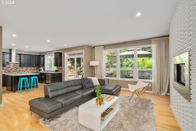 living room with light wood finished floors, recessed lighting, a healthy amount of sunlight, and baseboards