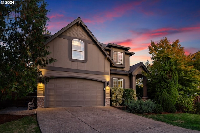 view of front of house featuring stone siding, driveway, a garage, and board and batten siding