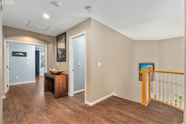 corridor featuring an upstairs landing, visible vents, baseboards, and wood finished floors