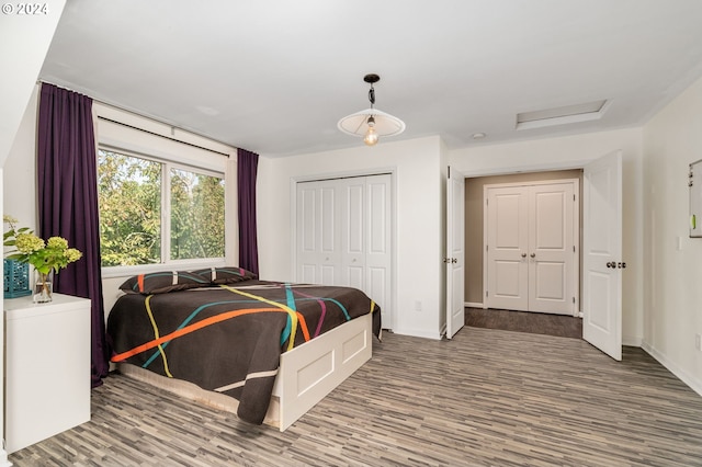 bedroom featuring a closet, attic access, baseboards, and wood finished floors