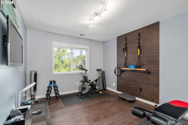 workout room featuring visible vents, wood finished floors, and baseboards