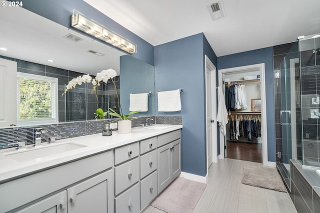 bathroom with a sink, visible vents, backsplash, and a shower stall