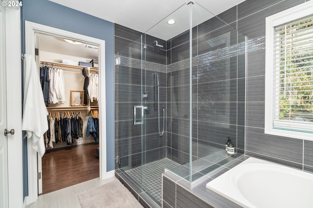 bathroom featuring tile patterned flooring, a shower stall, a bath, and a walk in closet