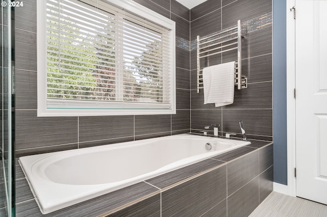 bathroom featuring tile patterned floors, tile walls, and a garden tub