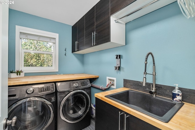 washroom with cabinet space, independent washer and dryer, and a sink