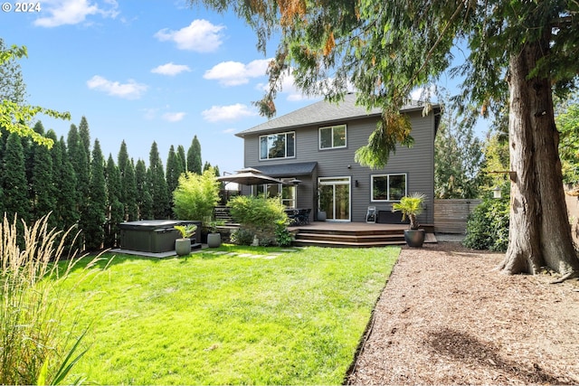 back of house featuring a wooden deck, fence, a lawn, and a hot tub