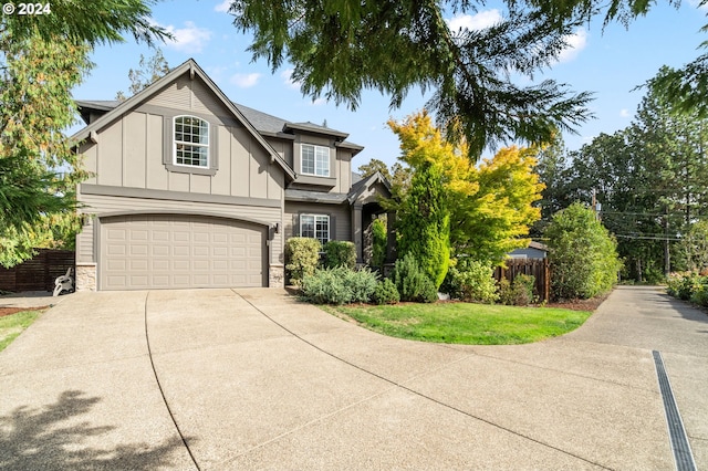 view of front of house featuring fence, concrete driveway, a garage, stone siding, and board and batten siding