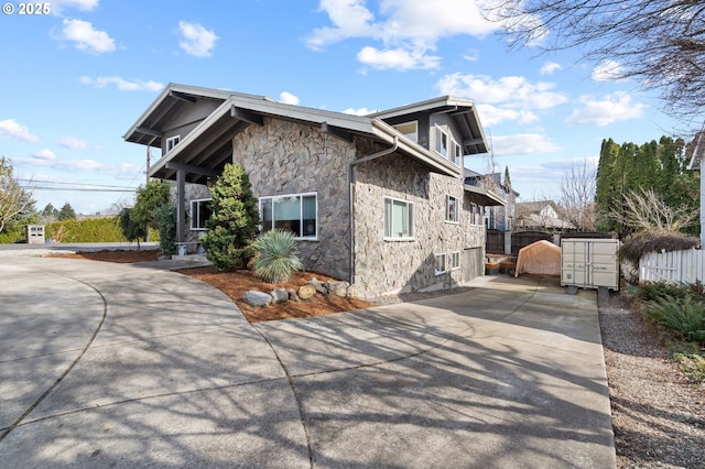 view of home's exterior with stone siding and fence