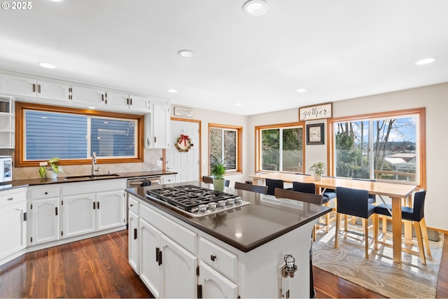 kitchen featuring appliances with stainless steel finishes, dark countertops, dark wood-type flooring, and a sink