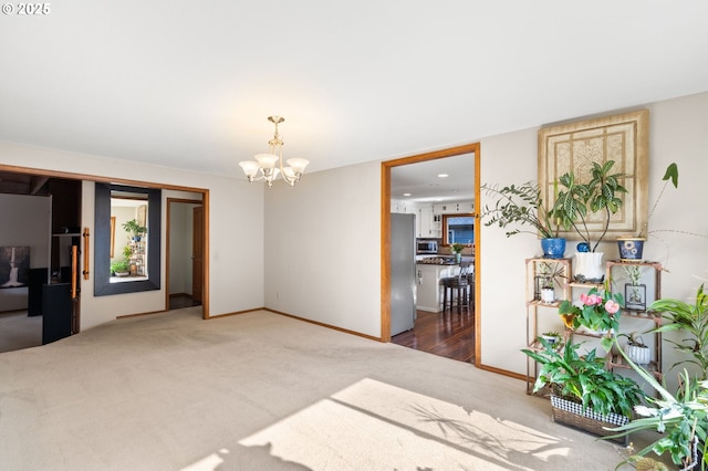 living area featuring carpet, a chandelier, and baseboards