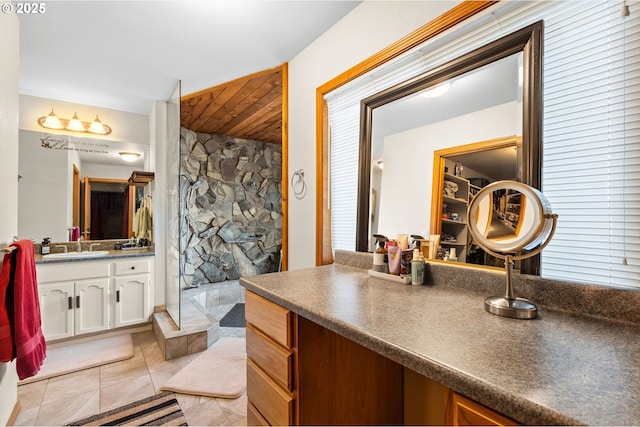 full bath with wooden ceiling, tile patterned floors, a tile shower, and vanity