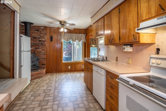 1772 SE Hamilton St, Roseburg, OR 97470 - kitchen featuring white appliances, a wood stove, under cabinet range hood, a sink, and brown cabinets