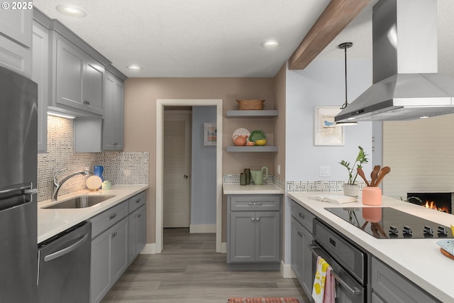 kitchen featuring a sink, light countertops, black appliances, island exhaust hood, and decorative light fixtures