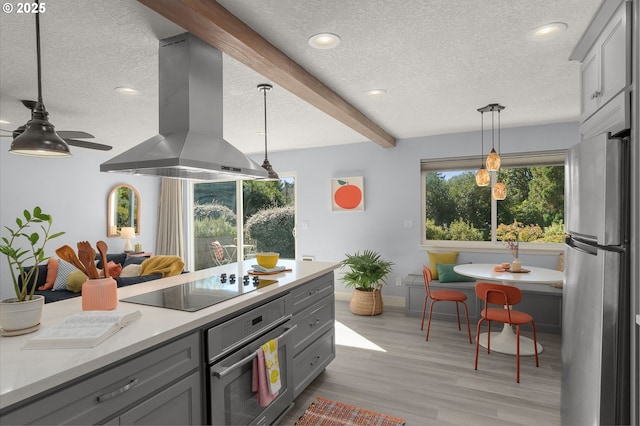 kitchen with appliances with stainless steel finishes, beamed ceiling, hanging light fixtures, island exhaust hood, and gray cabinetry