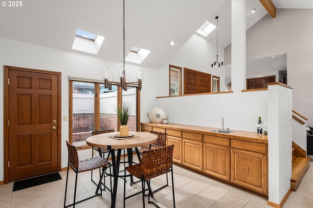 kitchen with beam ceiling, decorative light fixtures, high vaulted ceiling, light countertops, and a chandelier