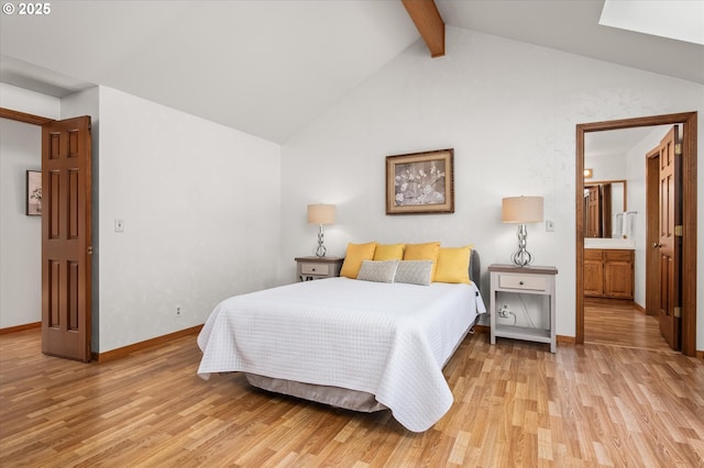 bedroom featuring light wood-type flooring, vaulted ceiling with beams, ensuite bath, and baseboards