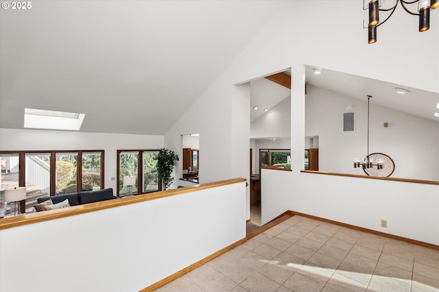 spare room with a skylight, visible vents, baseboards, an inviting chandelier, and high vaulted ceiling