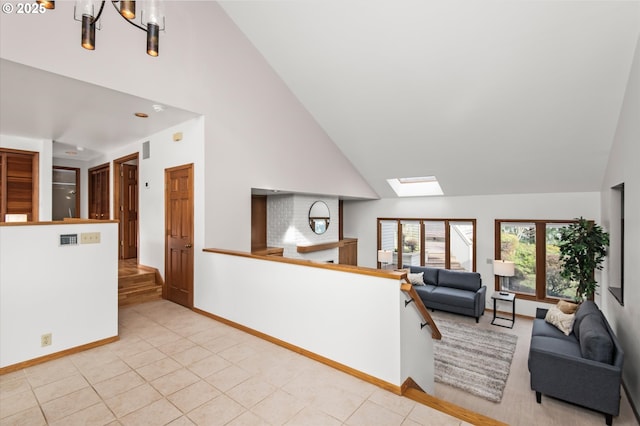 living area with light tile patterned floors, high vaulted ceiling, a skylight, and a notable chandelier