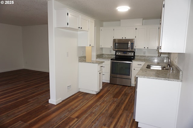 kitchen with white cabinets, dark wood finished floors, light stone counters, stainless steel appliances, and a sink