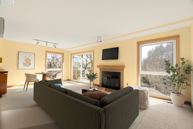 living room featuring track lighting, light carpet, and a tile fireplace