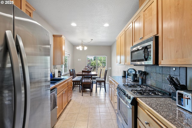 3647 Lodenquai Ln, Eugene, OR 97404 - kitchen with appliances with stainless steel finishes, dark countertops, a chandelier, tasteful backsplash, and a textured ceiling