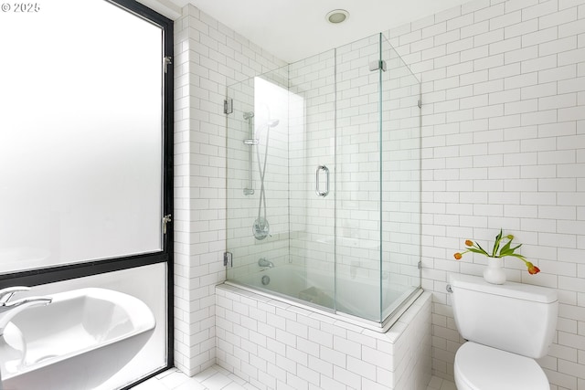 bathroom with tile walls, tiled shower / bath, and toilet