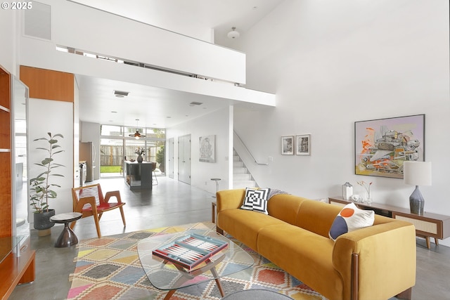 living area with visible vents, stairway, and a towering ceiling
