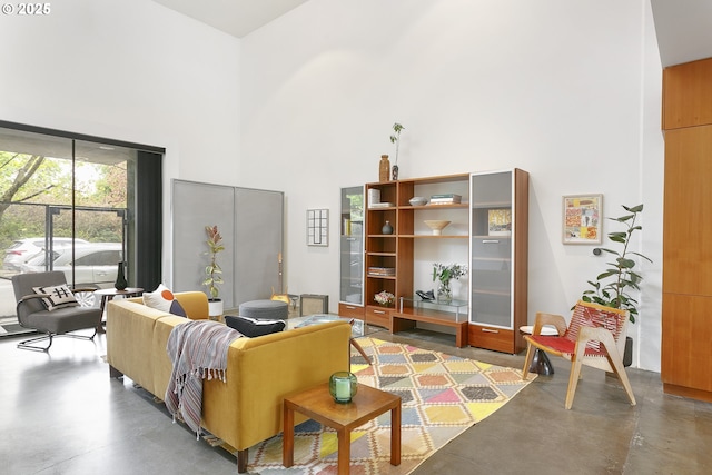 sitting room featuring a high ceiling and concrete floors