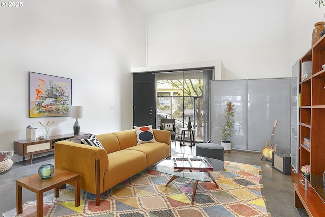 living room featuring a high ceiling and concrete flooring