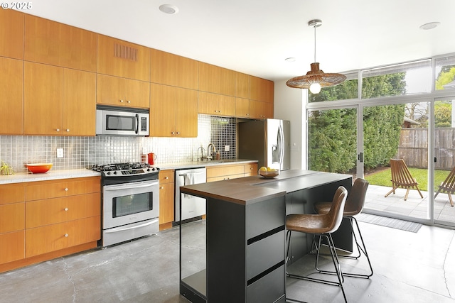 kitchen with visible vents, finished concrete flooring, a kitchen bar, backsplash, and stainless steel appliances
