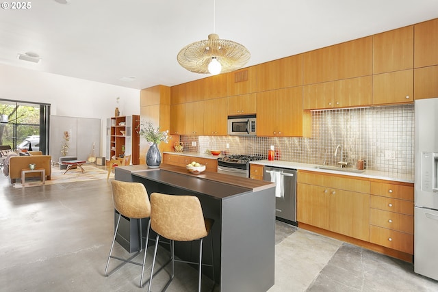 kitchen with appliances with stainless steel finishes, a sink, a breakfast bar area, a center island, and tasteful backsplash