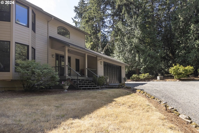 exterior space with a porch, a front lawn, and gravel driveway