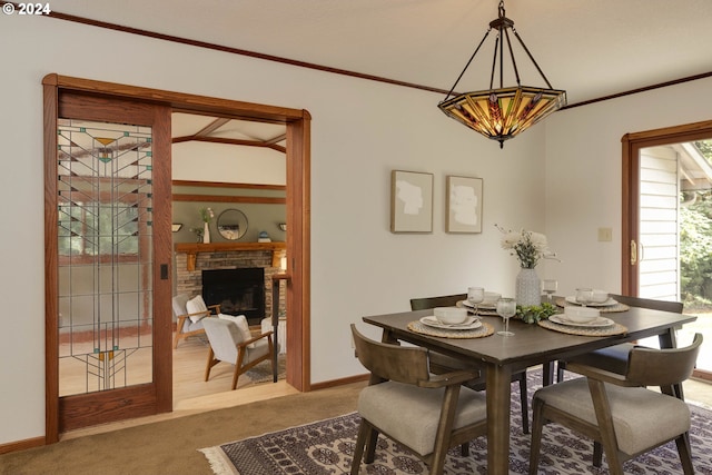 dining area featuring baseboards, ornamental molding, carpet flooring, a fireplace, and a chandelier