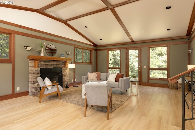 living area with lofted ceiling with beams, light wood-style flooring, a fireplace, and a wealth of natural light