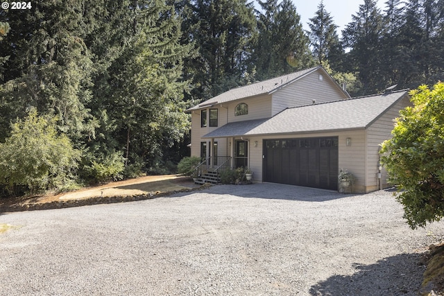 view of front of house featuring a shingled roof, gravel driveway, and an attached garage