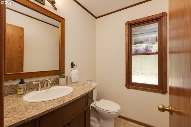 half bathroom with baseboards, toilet, ornamental molding, tile patterned flooring, and vanity