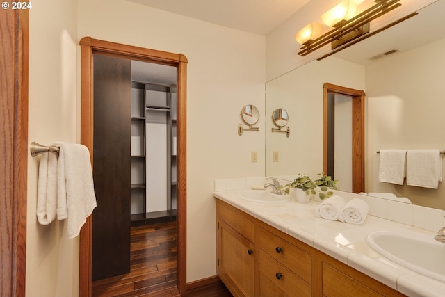 full bath featuring double vanity, visible vents, a sink, and wood finished floors