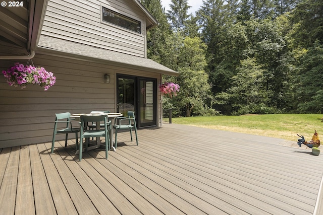 wooden terrace featuring outdoor dining area and a yard