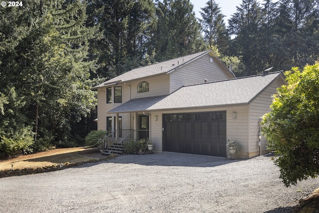 traditional-style house featuring roof with shingles, driveway, and an attached garage