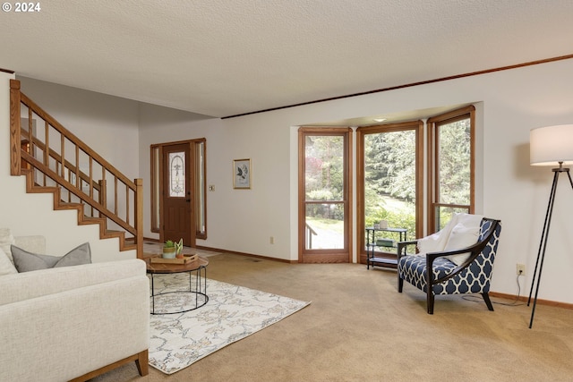 living area featuring light carpet, a textured ceiling, stairs, and baseboards