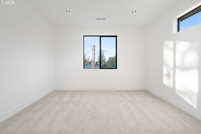 unfurnished room featuring light carpet and a wealth of natural light