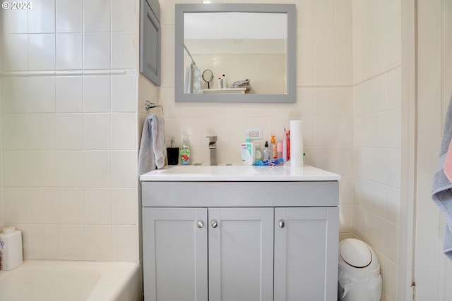 bathroom with tile walls, bathing tub / shower combination, and vanity with extensive cabinet space