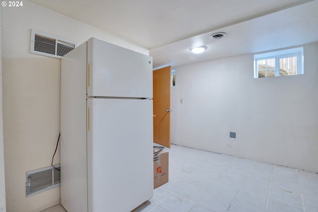 basement featuring white fridge and light tile flooring