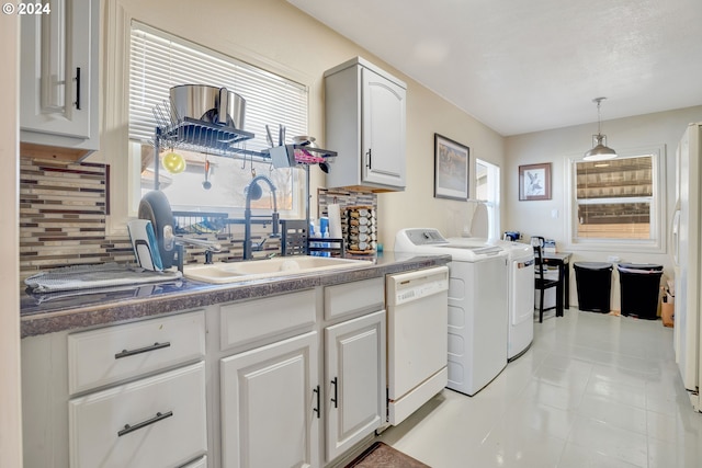 clothes washing area with light tile floors, plenty of natural light, washer and clothes dryer, and sink